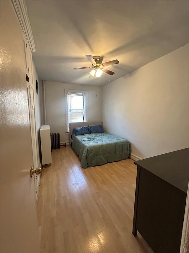 bedroom with ceiling fan, radiator, and light hardwood / wood-style flooring