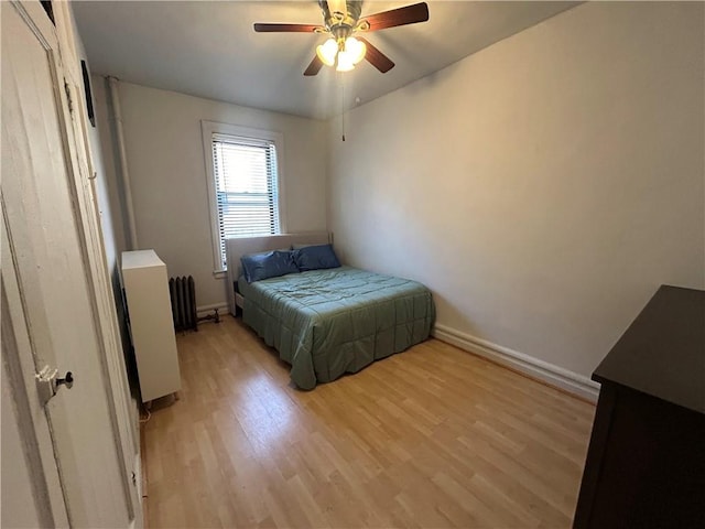 bedroom featuring ceiling fan, radiator heating unit, and light hardwood / wood-style flooring