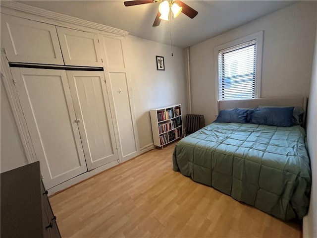 bedroom with ceiling fan, a closet, radiator heating unit, and light hardwood / wood-style flooring