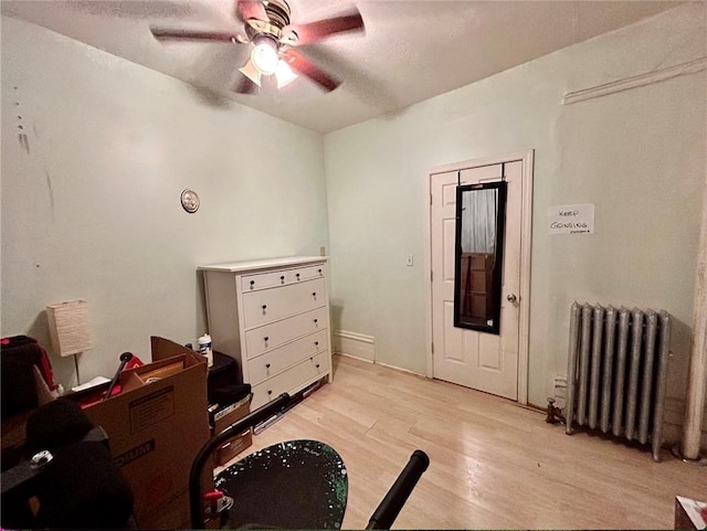 interior space featuring light wood-type flooring, radiator, and ceiling fan