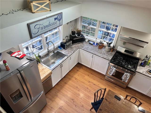 kitchen featuring light stone countertops, stainless steel appliances, sink, light hardwood / wood-style flooring, and white cabinets