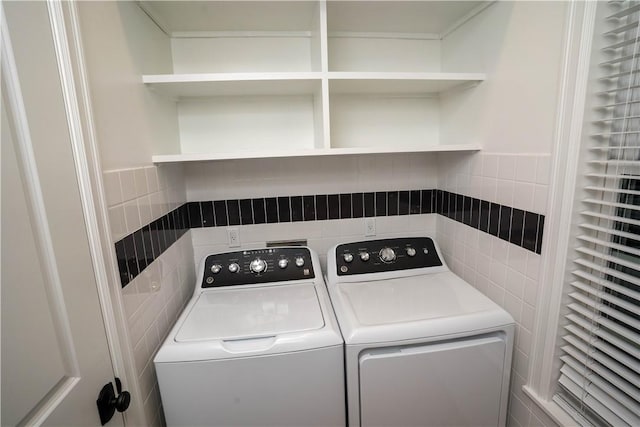 laundry room with separate washer and dryer and tile walls