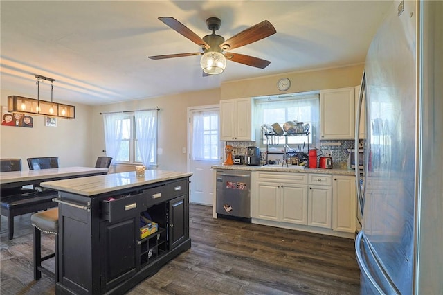 kitchen with appliances with stainless steel finishes, tasteful backsplash, a center island, dark hardwood / wood-style floors, and white cabinetry