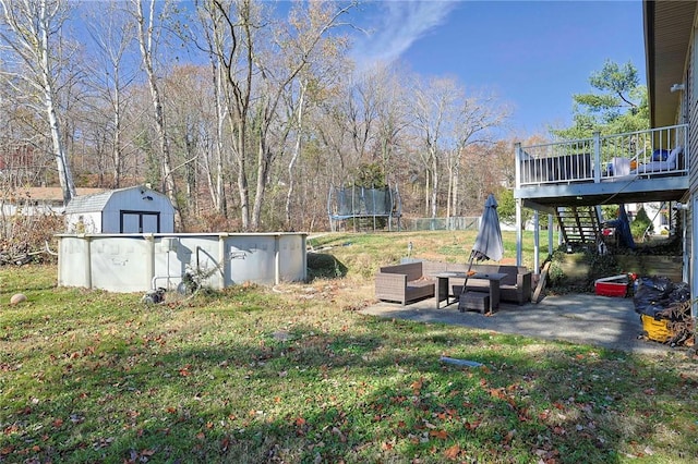 view of yard featuring a storage shed, a pool side deck, a patio, and a trampoline