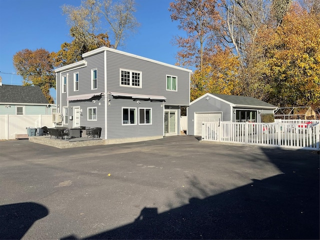 rear view of property featuring a garage, an outbuilding, and a patio