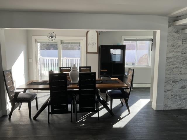 dining area with an inviting chandelier, dark hardwood / wood-style flooring, and a baseboard heating unit