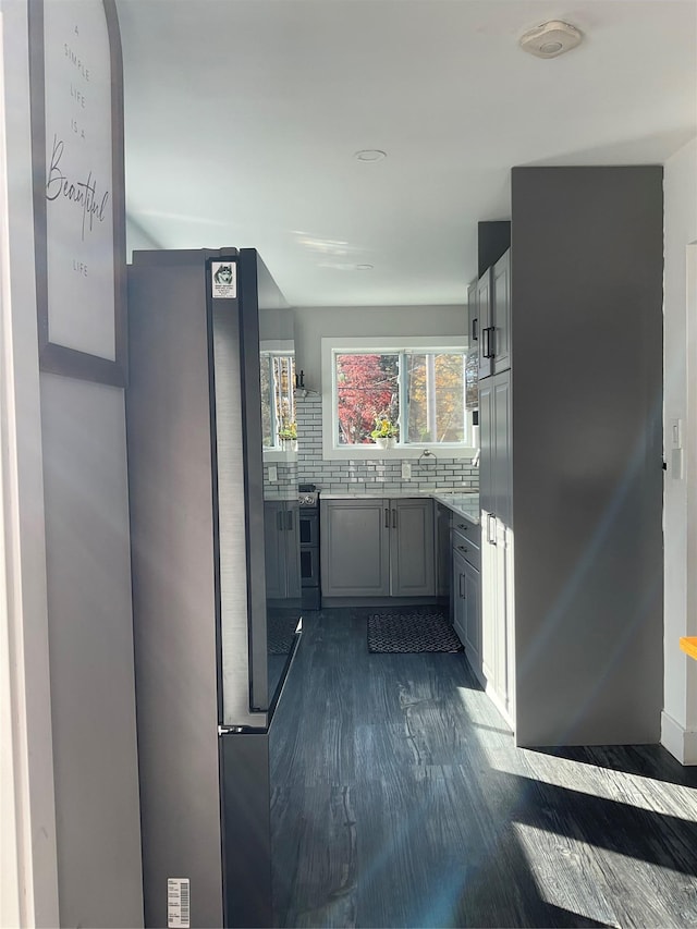 kitchen featuring gray cabinets, dark hardwood / wood-style flooring, stainless steel refrigerator, and tasteful backsplash