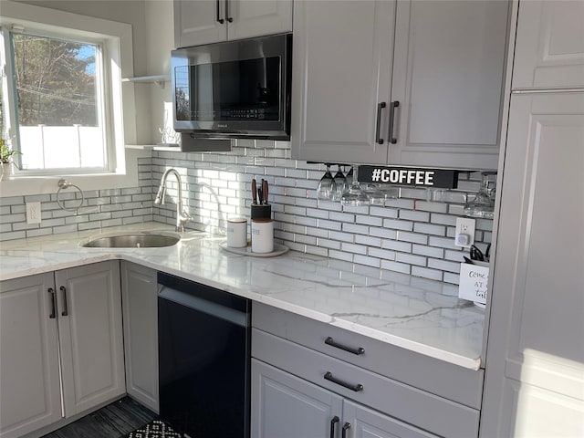 kitchen with light stone counters, dishwasher, white cabinets, and sink