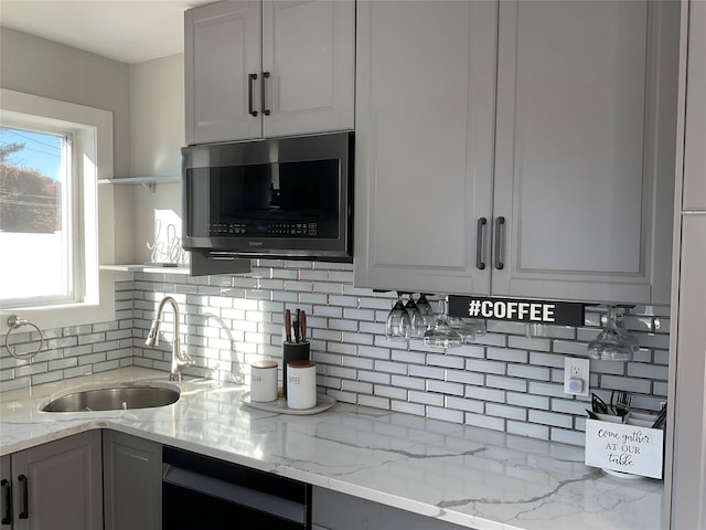 kitchen featuring backsplash, sink, dishwashing machine, light stone counters, and white cabinetry