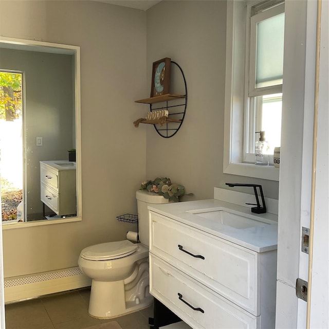 bathroom featuring tile patterned flooring, vanity, a healthy amount of sunlight, and a baseboard heating unit