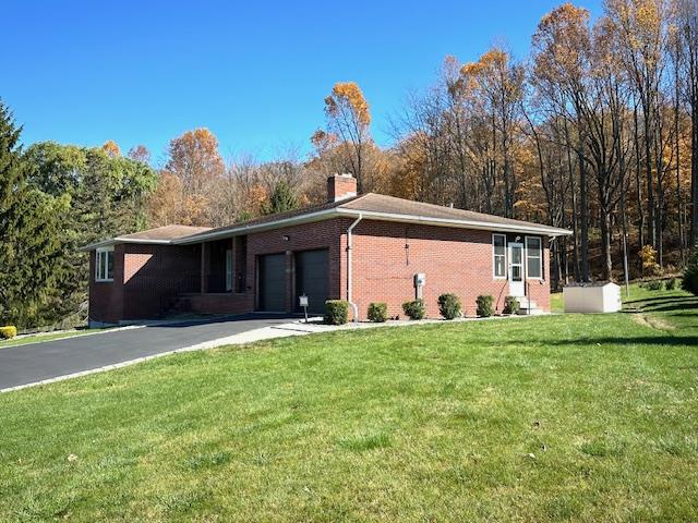 ranch-style house featuring a garage and a front lawn