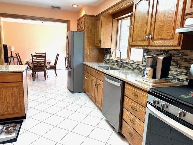 kitchen with light stone countertops, sink, ventilation hood, decorative backsplash, and appliances with stainless steel finishes