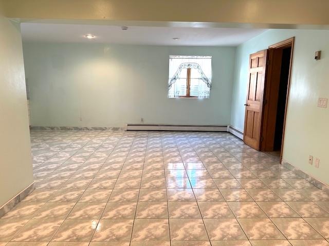 unfurnished room with light tile patterned flooring and baseboard heating