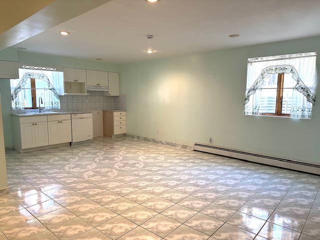 kitchen featuring white cabinetry, dishwasher, sink, baseboard heating, and backsplash