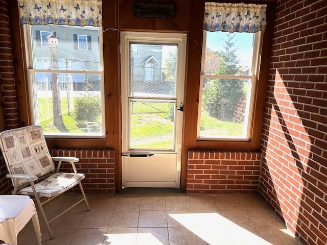 entryway with light tile patterned floors and brick wall