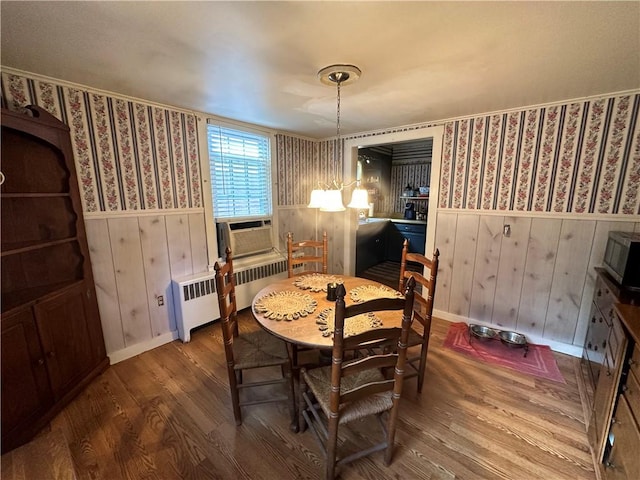 dining area featuring hardwood / wood-style floors, a notable chandelier, cooling unit, and radiator