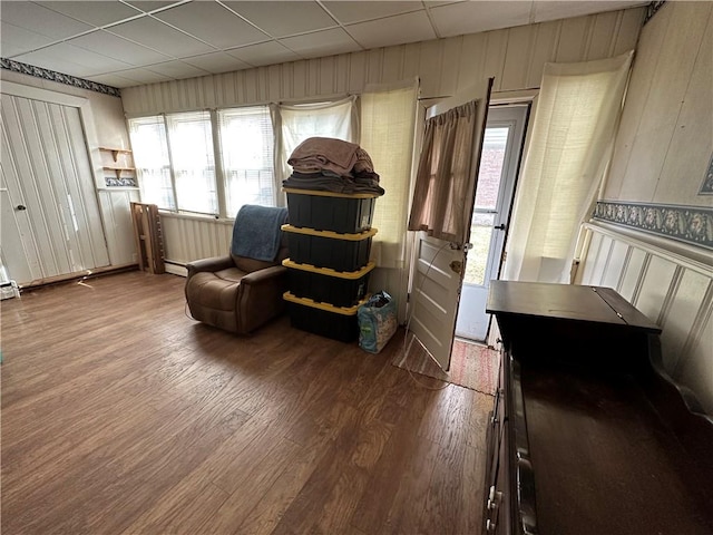 living area featuring a drop ceiling and wood-type flooring