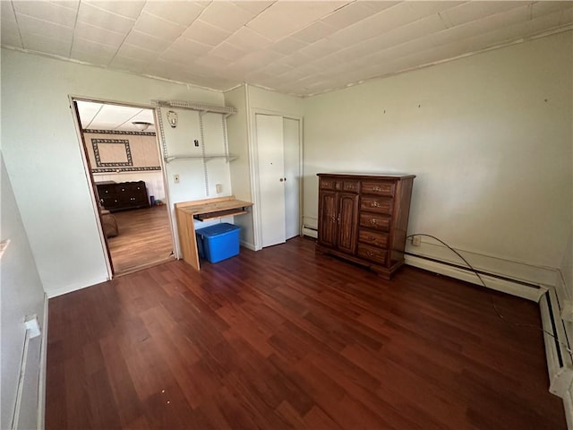 unfurnished bedroom featuring dark hardwood / wood-style flooring and baseboard heating