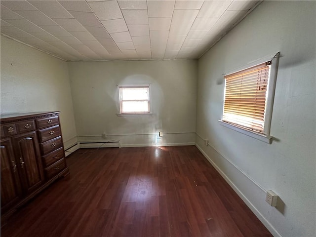 empty room with dark hardwood / wood-style flooring and a baseboard heating unit