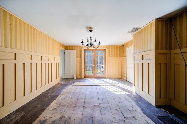 unfurnished room featuring hardwood / wood-style flooring, french doors, and an inviting chandelier