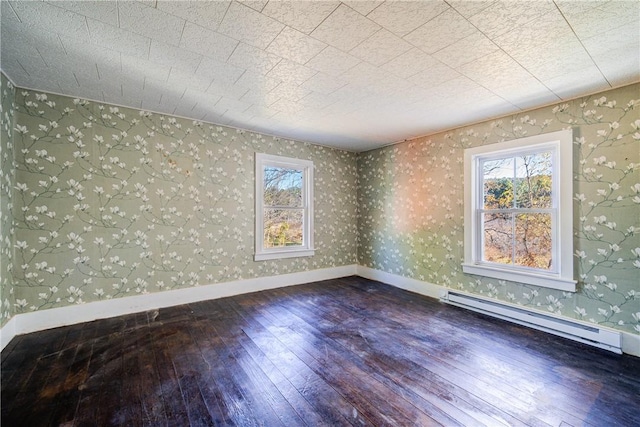 empty room featuring baseboard heating and dark wood-type flooring