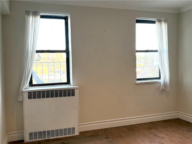 spare room with radiator, hardwood / wood-style floors, and a healthy amount of sunlight