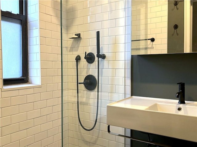 bathroom with a tile shower, plenty of natural light, and sink