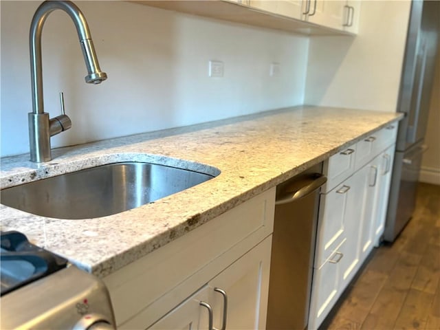 kitchen featuring white cabinets, dark hardwood / wood-style floors, light stone counters, and sink