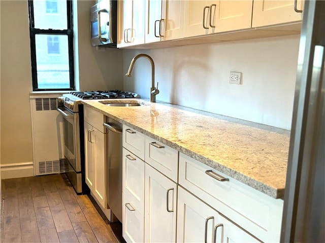 kitchen featuring white cabinets, dark hardwood / wood-style floors, light stone countertops, and appliances with stainless steel finishes