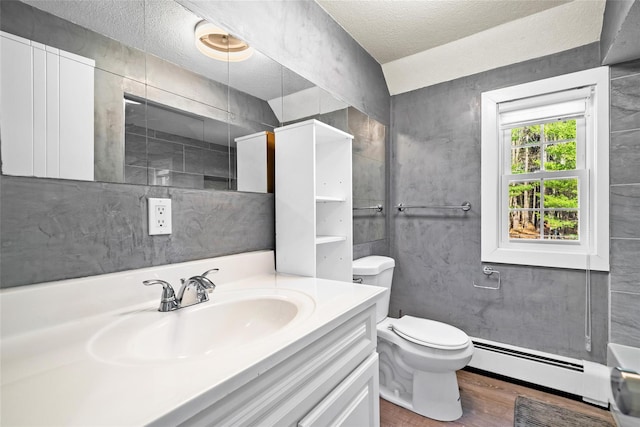 bathroom with hardwood / wood-style floors, vanity, toilet, a textured ceiling, and a baseboard radiator