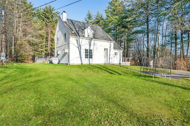 rear view of house featuring a trampoline and a yard