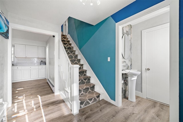 staircase featuring hardwood / wood-style flooring, sink, and a baseboard radiator