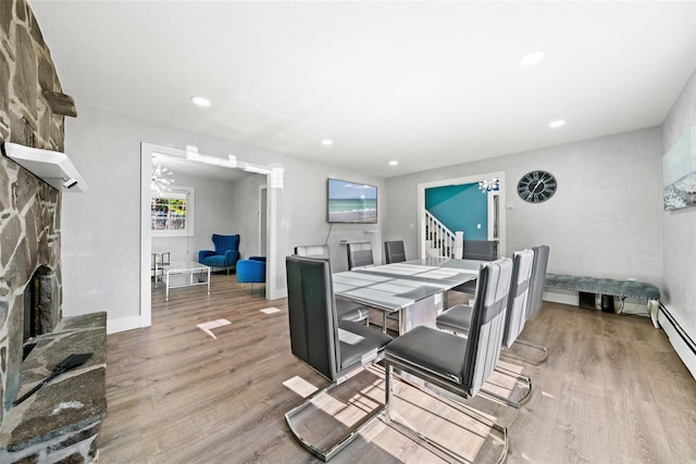 dining room featuring light wood-type flooring, a fireplace, and baseboard heating