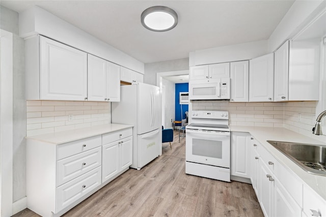 kitchen with white appliances, backsplash, white cabinets, sink, and light wood-type flooring