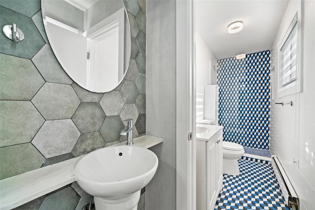 bathroom featuring a bathing tub, baseboard heating, toilet, vanity, and tile walls