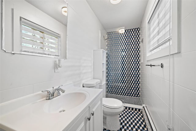 bathroom with a tile shower, a textured ceiling, toilet, and tile walls