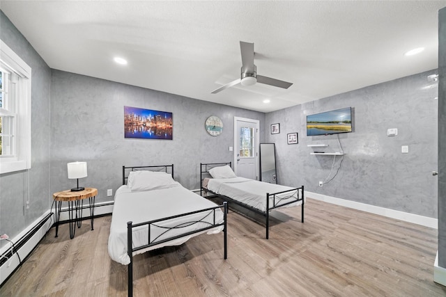 bedroom featuring baseboard heating, ceiling fan, and hardwood / wood-style floors