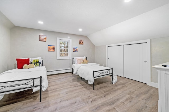 bedroom featuring lofted ceiling, light wood-type flooring, baseboard heating, and a closet