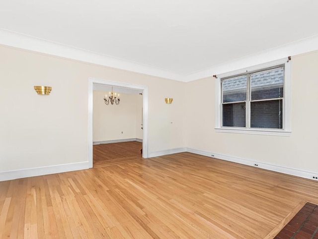 empty room with hardwood / wood-style floors and a notable chandelier