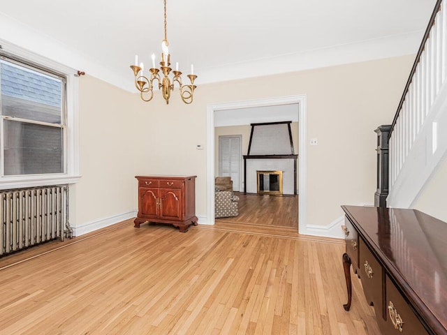 interior space with an inviting chandelier, radiator, and light hardwood / wood-style flooring