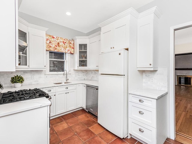 kitchen featuring backsplash, sink, white cabinets, and white appliances