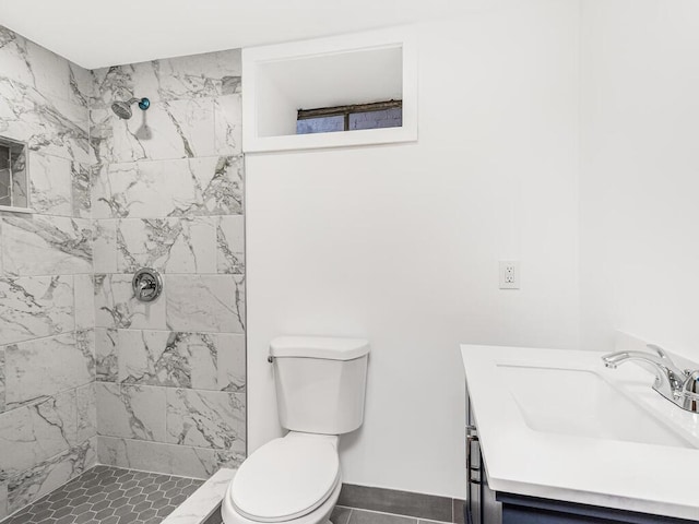 bathroom with a tile shower, vanity, toilet, and tile patterned floors