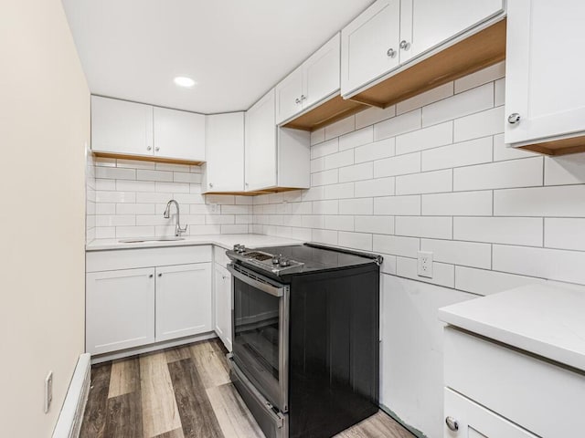 kitchen featuring black range with electric stovetop, sink, decorative backsplash, white cabinets, and hardwood / wood-style flooring