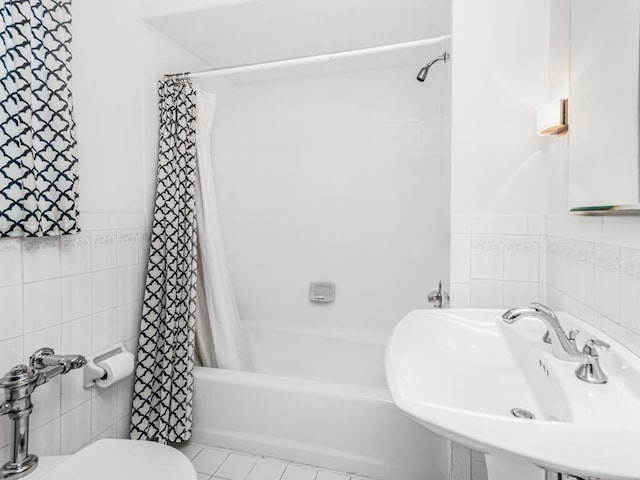 full bathroom with shower / tub combo, tile patterned floors, tile walls, and sink