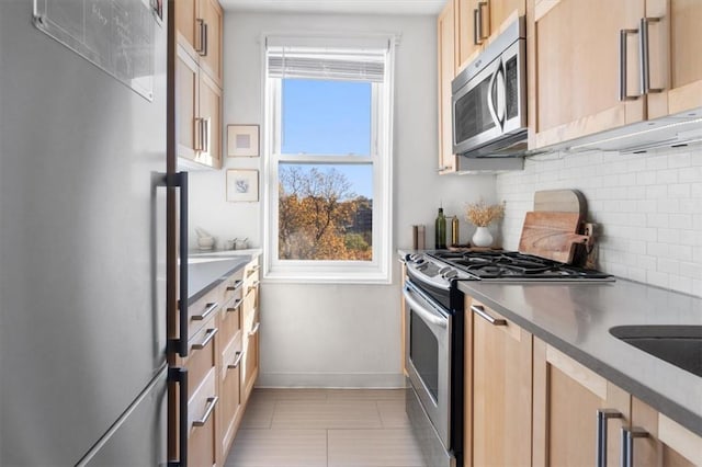 kitchen with decorative backsplash, light brown cabinets, light tile patterned floors, and appliances with stainless steel finishes