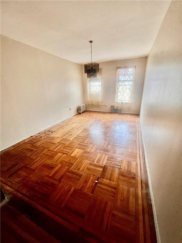 spare room featuring radiator heating unit and an inviting chandelier