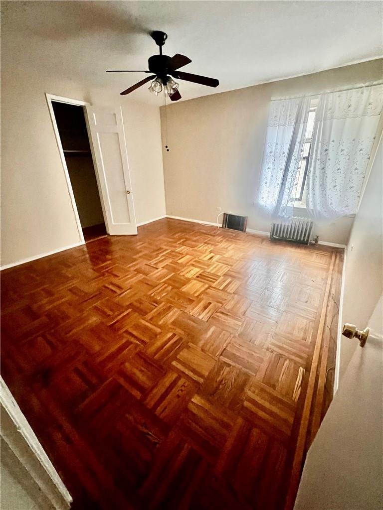 spare room with ceiling fan, parquet flooring, and radiator