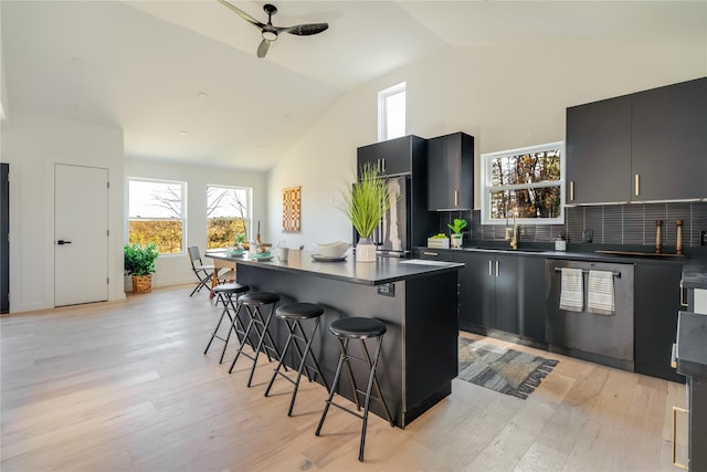 kitchen with sink, stainless steel dishwasher, lofted ceiling, a breakfast bar area, and a kitchen island