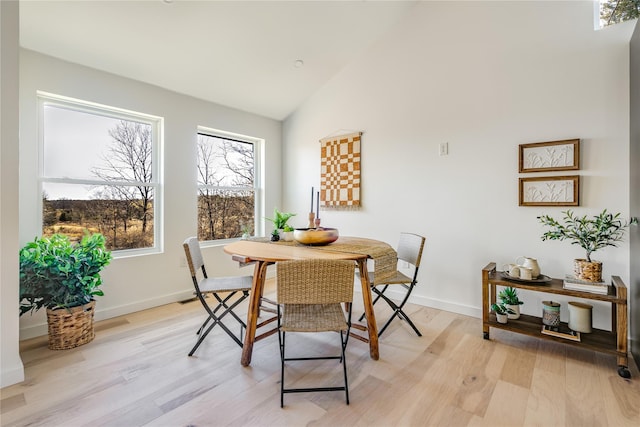 dining area with light hardwood / wood-style floors and vaulted ceiling