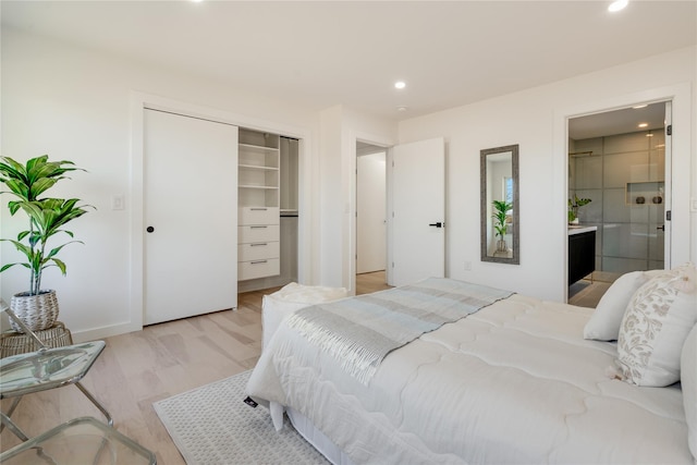 bedroom with a closet, connected bathroom, and light hardwood / wood-style flooring